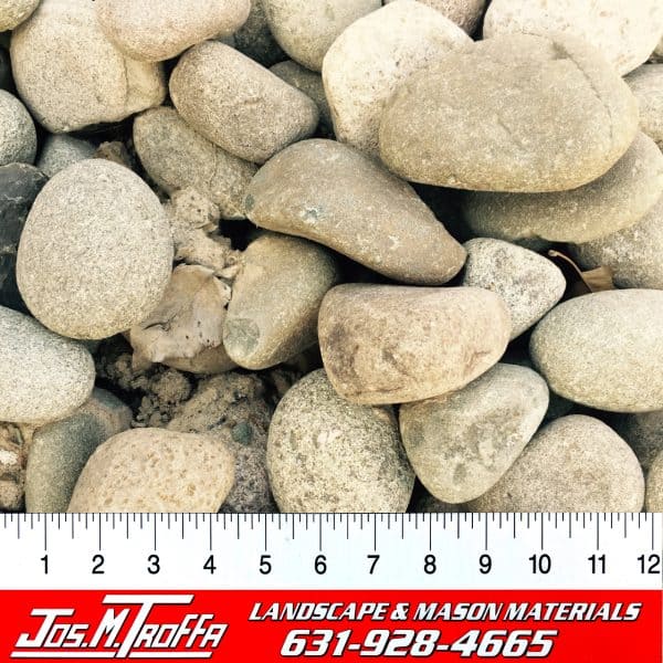 Smooth, rounded pebbles in varying shades of gray shown with a ruler for scale, from Jos. M. Troffa Landscape & Mason Materials in Long Island, NY
