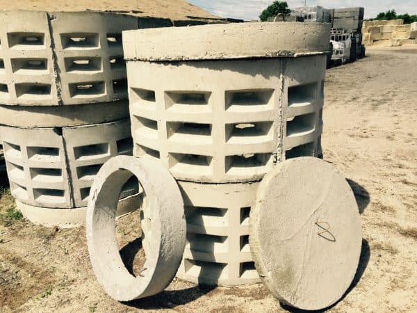 Concrete drainage components, including cylindrical and circular pieces, stored in an outdoor yard for infrastructure projects in Long Island, NY.