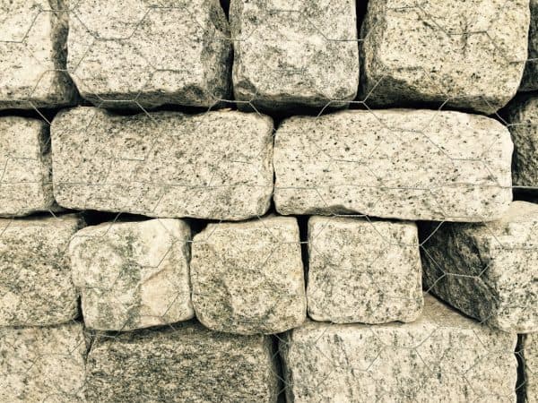 Stack of rectangular gray stone blocks secured with wire mesh, commonly used for landscaping or retaining walls in Long Island, NY.
