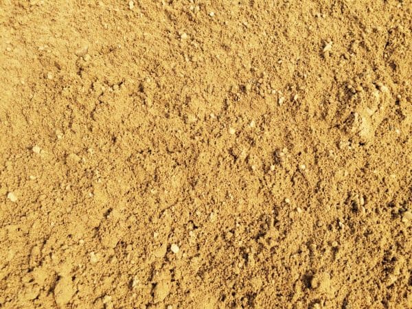 Close-up of a granular, light brown soil or sand surface, commonly found in natural landscapes or used in gardening in Long Island, NY.