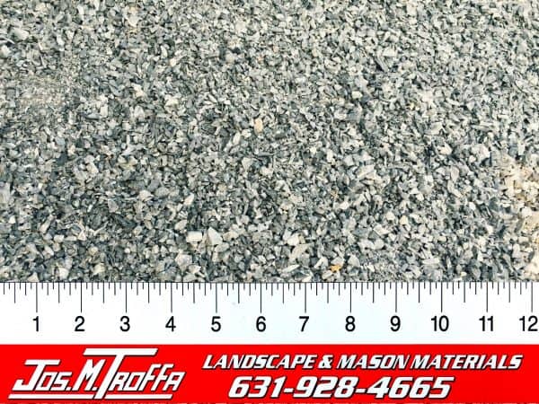 Close-up of small gravel pieces with a ruler for scale, promoting materials from JOS. M. TROFFA Landscape & Mason Materials in Long Island, NY.